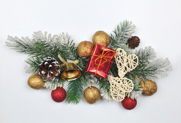 Festive  border from pine tree branches ,decorative balls, cones, nuts, bell, gift and rattan hearts on white background. Top view, flat lay. Christmas greeting concept. Free space for message