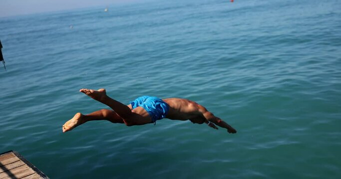 A man dives into the sea from a wooden pier
