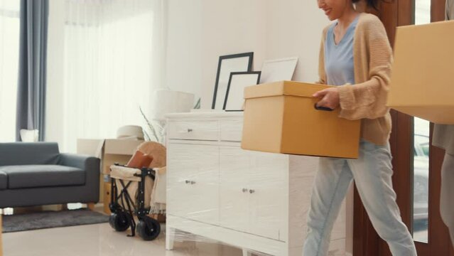 Young Asian couple help each other moving carton box full of stuff get some rest sit on sofa couch in living room at new house. Husband and wife move new house, Apartment Rent And Ownership Concept.