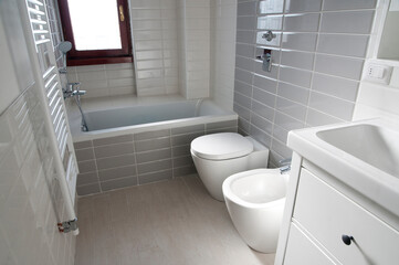 bathroom with gray tile covering and floor-mounted sanitary fixtures

