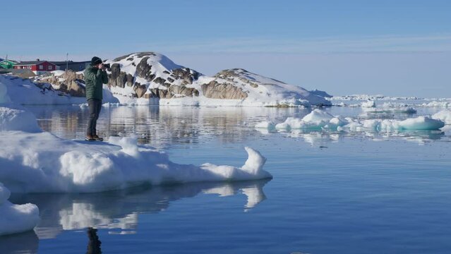 Wide Shot Of A Man Taking Pictures Of The Icebergs While On Top Of The Ice