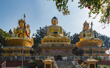 three Buddha statues in gold in a worship park near Kathmandu city