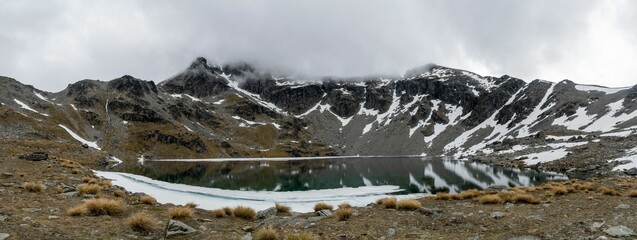 Panoramic view of Lake Alta with clouds over it in winter in Queenstown, New Zealand.