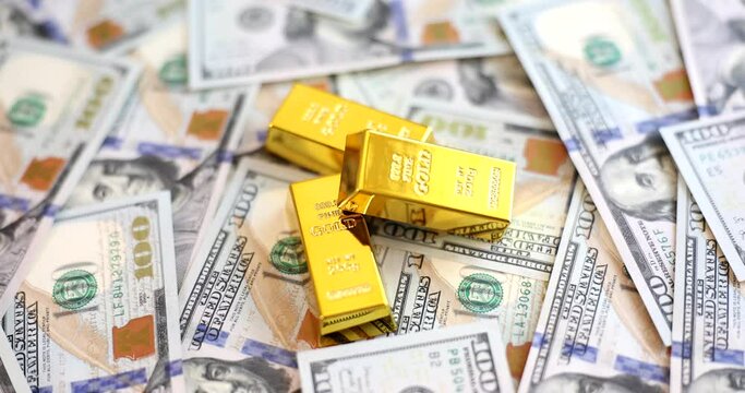 Gold ingots lie on scattered money, a close-up