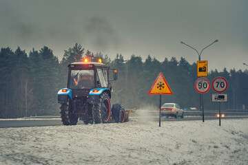 Tractor with snow plow plowing highway, clearin snow from roadway, prevent slipping on road. Plow...