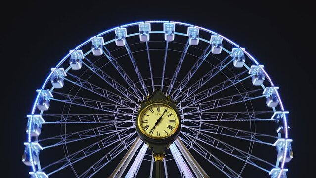 Ferris wheel for Christmas, behind the public Parliament clock in Bucharest, Romania, centered and symmetrical. Night timelapse, lights, illuminated, symmetry.