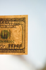 Hundred dollar bill in bright sunlight. Close-up with a blurred background.