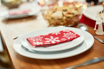 Youre invited. Christmas, celebration and holiday table plate for food, party and dining place setting zoom. Dining room, lunch or dinner to celebrate xmas vacation with festive red snowflake napkin.