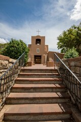 San Miguel Chapel in Santa Fe, New Mexico with brown steps leading to it under a sunny blue sky