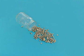 Gallstones next to specimen jar on blue background