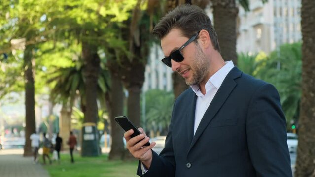 Young casual Businessman holding and using smartphone for sms messages. business, lifestyle, technology and Social media network concept. a man in a business suit stands on the street with a phone