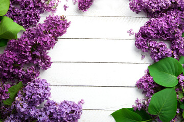 Flower frame for text with bouquets of purple lilacs on white wooden table with space for text in the center, without anybody.