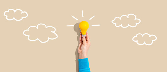 Person holding a yellow light bulb with cloud sketches