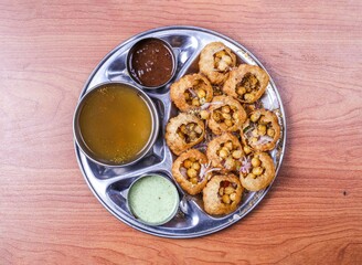 pani puri or gol gappay with raita, sweet sauce and spicy water served in dish isolated on table...