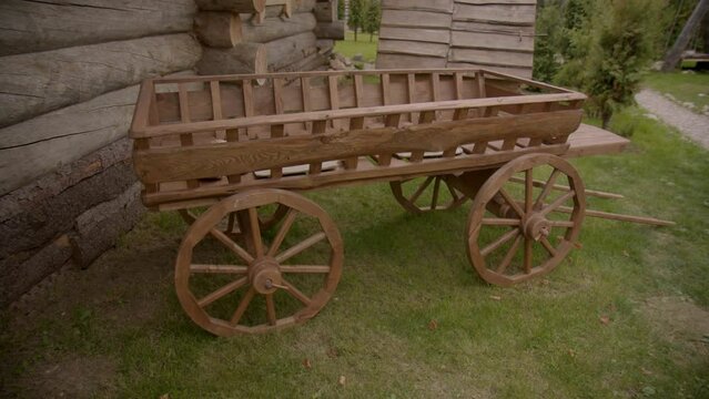 Decorative wooden wagon next to house of large logs wooden well. Elements of decoration of yard of bath resort.