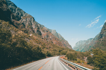 Fototapeta premium Empty road leading to the mountains on a moody day in Norway with clouds