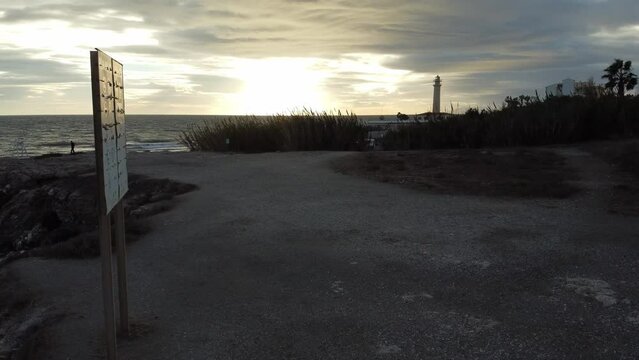 Drone footage above the shore and Torrox Lighthouse during bright cloudy sunset