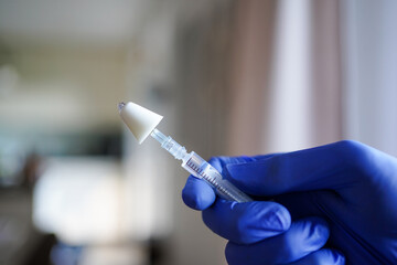 Hand holding a syringe with a mucosal atomization decive (MAD) used for intranasal application of...