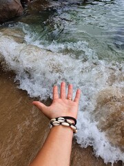Mão estendida em direção as ondas do mar
