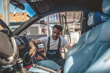 Concentrated auto detailer vacuum-cleaning the vehicle upholstery