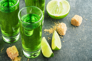 Absinthe. Two glasses of absinthe with cane sugar and lime on dark background. Strong alcoholic drink. Bar card concept. Place for text.