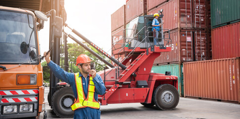 Engineer or foreman working and use talkie at container yard while wearing PPE., Logistics concept inside the shipping, import, and export industries.