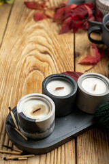Assorted candles, leaves on a wooden background, warm knitted sweater, flat lay,