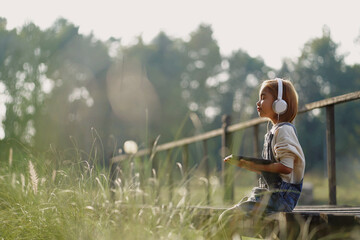 A little girl is using a smartphone and headphones to listen to music. social media, internet, education technology