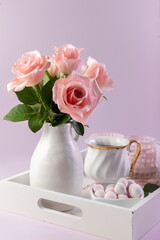 A bouquet of roses in a vase, sweets near a cup of coffee on a white tray. Card. Romantic breakfast. Photo