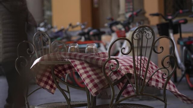 Wind flowing on restaurant tablecloth in Italian street. Empty business in Europe. Table Linens Checkpoint. A classic gingham print