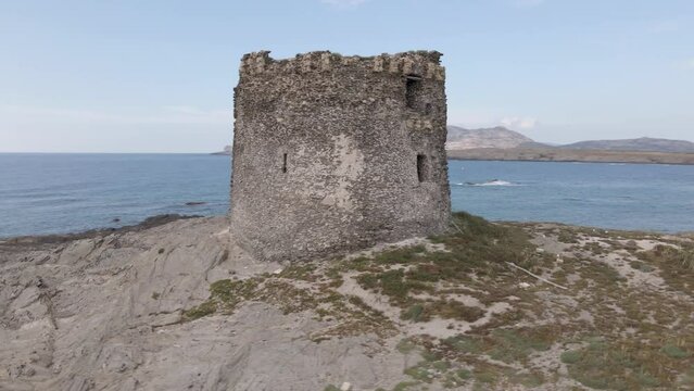 Old castle isolated on the Spiaggia della Pelosetta beach surrounded by rocks
