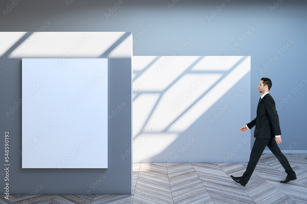 Poster side view of blurry business man walking in spacious gallery interior with empty poster and sunlight