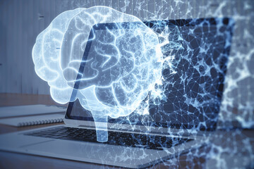 Close up of table with computer and abstract glowing polygonal human brain hologram on blurry background. Digital intelligence, ai and future concept. Double exposure.