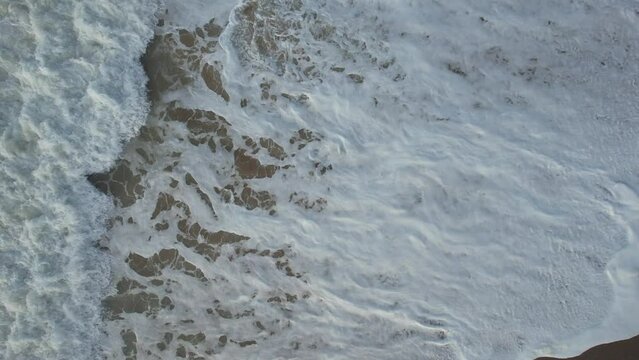 Aerial view from drone in Bidart France of beauty of nature with the foam of the ocean which is swallowed up in the water by the force of the waves and which leaves in visual a divine abstract texture
