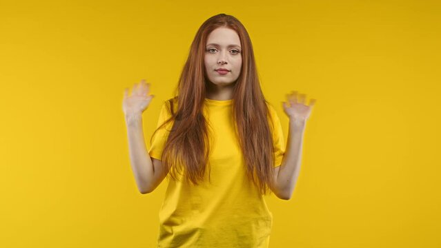 Uninterested woman disapproving with NO hand sign gesture, it's not me, I can't help. Denying, rejecting, disagree. Portrait of young lady on yellow background.