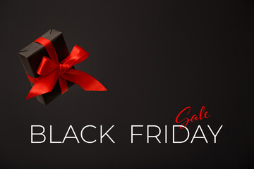 Black Friday sale. Black gift box with red bow floating in air on black background. Discount, online shopping concept.