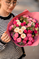bouquet with roses and thistles in wrapping paper in hands of woman