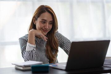 Asian businesswoman thinking Analyze the expected and proud performance of the business in her office.