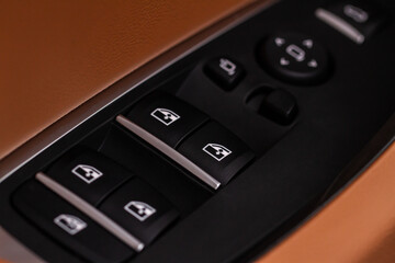 Obraz premium Close up view of button controlling window in modern car interior. Vehicle interior detail. Door handle with windows controls