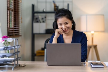 Portrait of Happiness Asian Woman of Asian businesswoman working on her laptop in her home office. online meeting happy rest time.