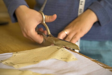 The fashion designer cuts the fabric according to patterns with scissors.