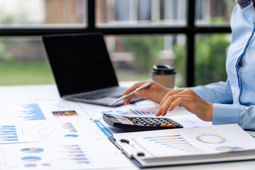 Asian business ideas are thinking and calculating with a calculator. front view of hand pointing to business data chart to calculate analysis Company financial processing.