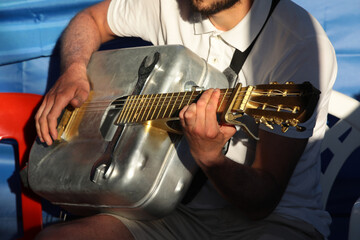 A man playing an iron hippie guitar with a musical instrument close-up