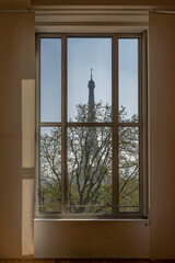 Paris, France - 03 26 2022: View of the Eiffel Tower and a tree through a window