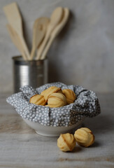Bowls of tasty walnut shaped cookies with boiled condensed milk on grey background