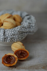 Bowls of tasty walnut shaped cookies with boiled condensed milk on grey background