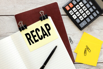 Recap sticker on a notebook with text. working table