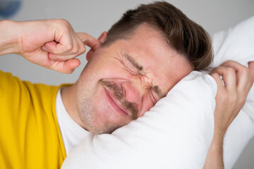 Obraz premium Portrait of Young Caucasian man in bed angry about noise 