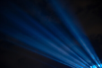 Blue spotlight rays with dark sky.