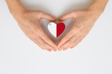 National flag of the Malta in the shape of a heart in female hands